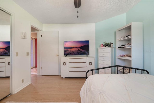 bedroom with ceiling fan, a textured ceiling, and light wood-type flooring