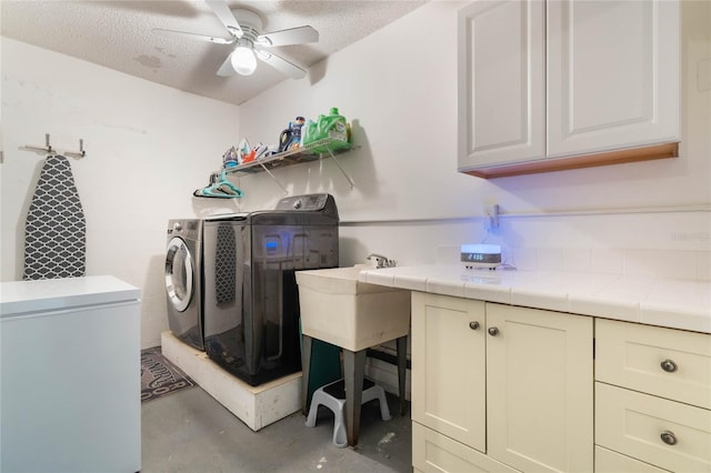 laundry area with cabinets, ceiling fan, a textured ceiling, and independent washer and dryer