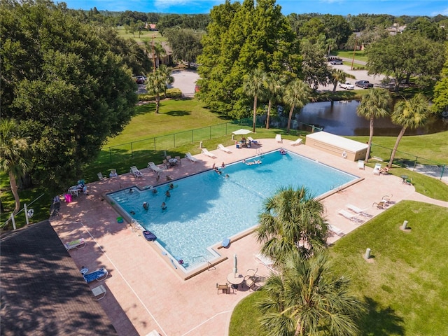 view of swimming pool featuring a patio area, a water view, and a lawn