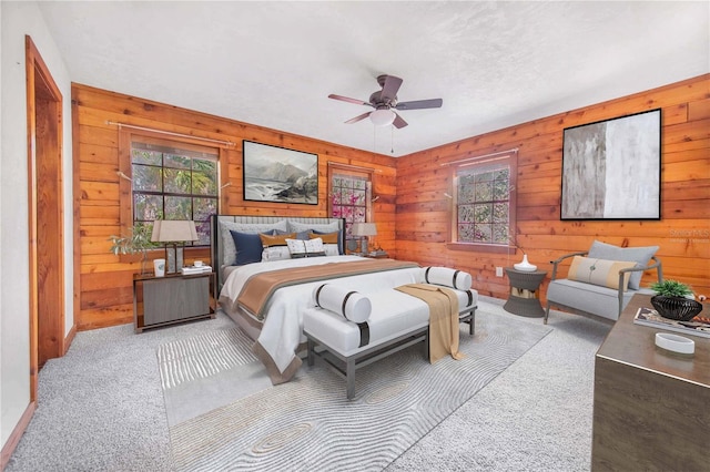 bedroom featuring carpet flooring, wood walls, and ceiling fan