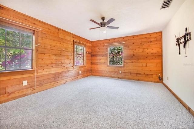 unfurnished room with wooden walls, visible vents, ceiling fan, and carpet