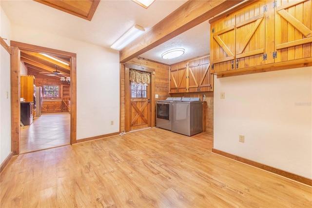 laundry area featuring cabinet space, light wood-style flooring, wooden walls, and washing machine and dryer