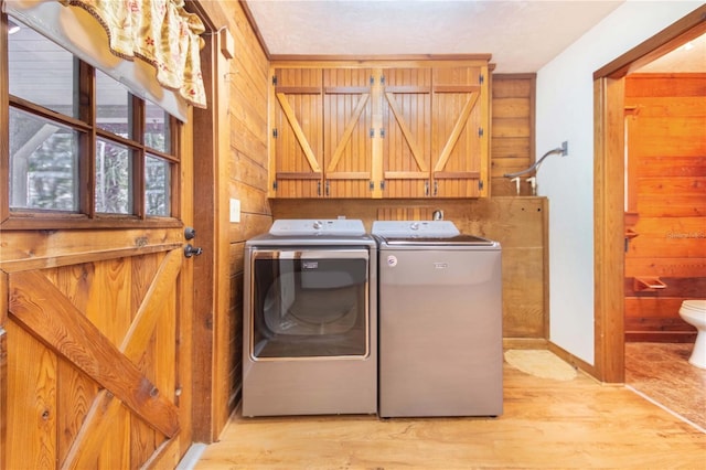 laundry room with washer and dryer, wooden walls, and wood finished floors