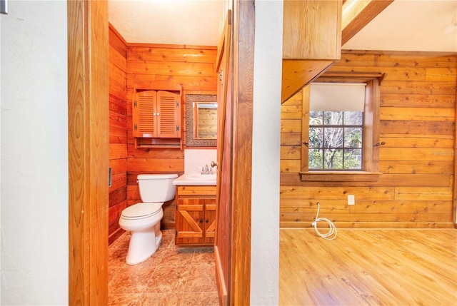 bathroom featuring tile patterned floors, wood walls, and toilet