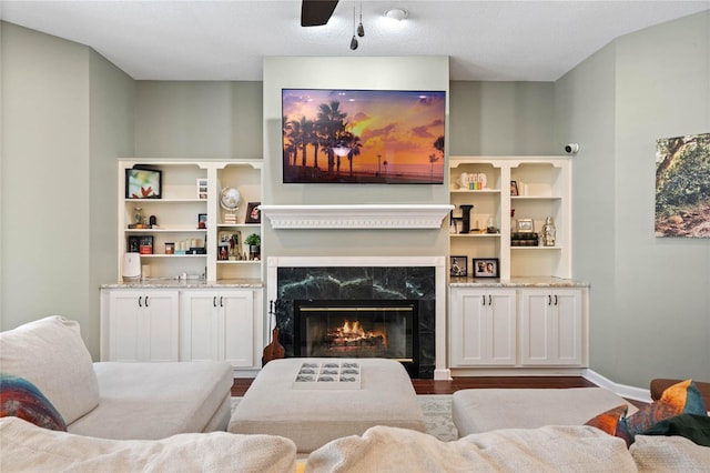 living room featuring wood-type flooring, ceiling fan, and a fireplace