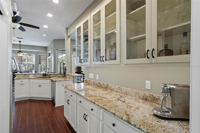 kitchen with sink, ceiling fan, white cabinetry, hanging light fixtures, and light stone countertops