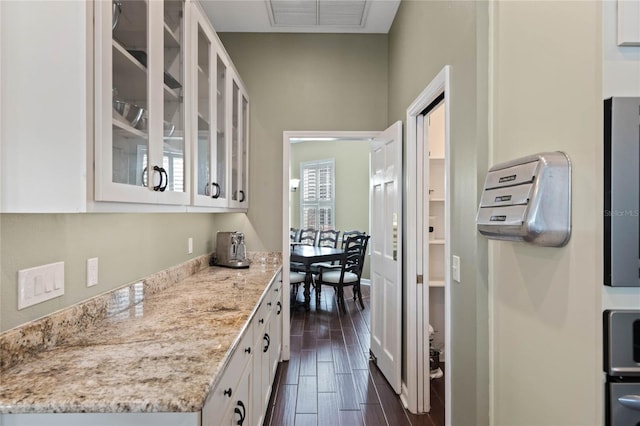 kitchen with white cabinetry, dark wood-type flooring, and light stone counters