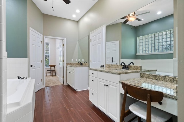 bathroom featuring vanity, a relaxing tiled tub, and ceiling fan