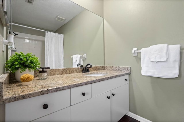 bathroom featuring vanity, a textured ceiling, and walk in shower