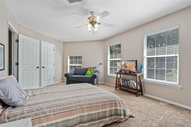 bedroom featuring ceiling fan, light carpet, and a textured ceiling