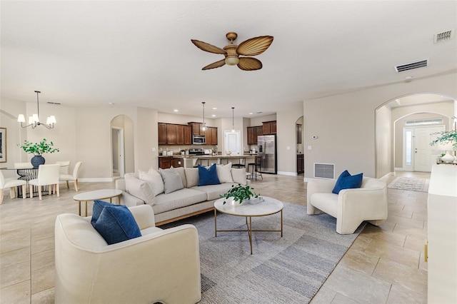 living room featuring ceiling fan with notable chandelier