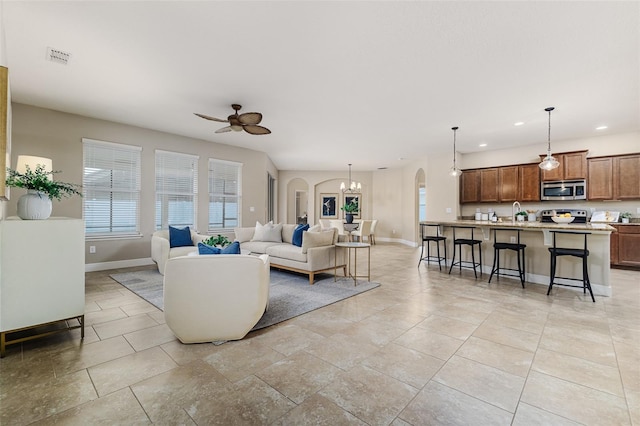 living room with sink and ceiling fan with notable chandelier