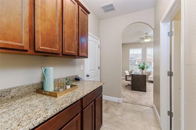 kitchen with light stone counters, ceiling fan, and light tile patterned flooring