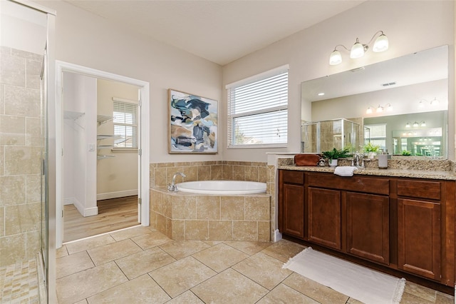 bathroom featuring vanity, independent shower and bath, tile patterned flooring, and a wealth of natural light