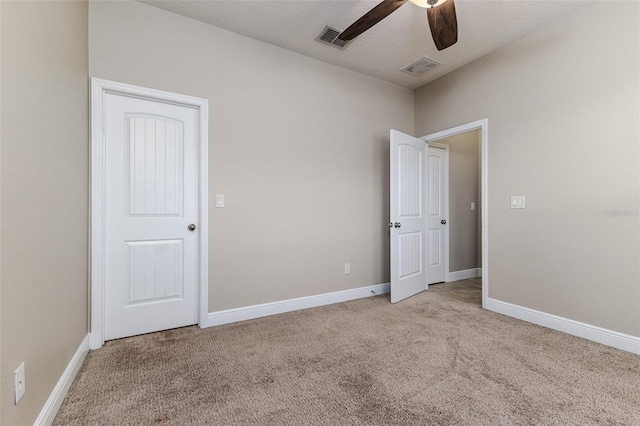 spare room with ceiling fan, light carpet, and a textured ceiling