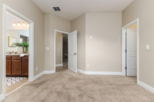 unfurnished bedroom with connected bathroom, sink, and light colored carpet