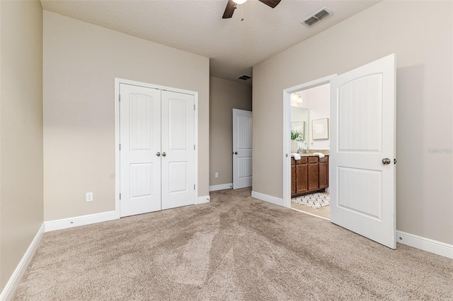 unfurnished bedroom featuring ensuite bathroom, light carpet, ceiling fan, and a closet