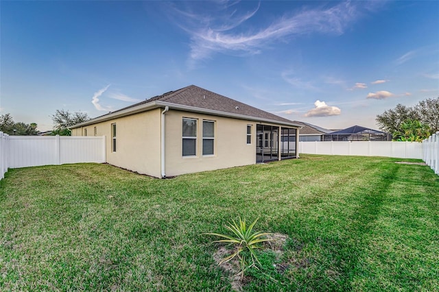 back of property featuring a sunroom and a yard