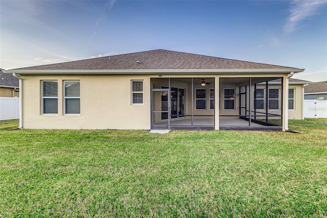 rear view of property featuring ceiling fan, a yard, a patio area, and a sunroom