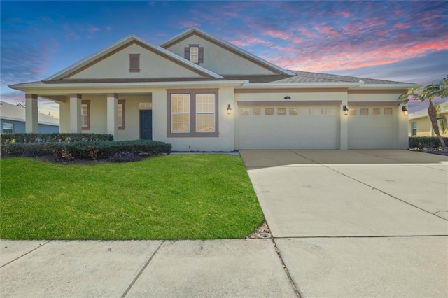 greek revival house with concrete driveway, a lawn, a garage, and stucco siding