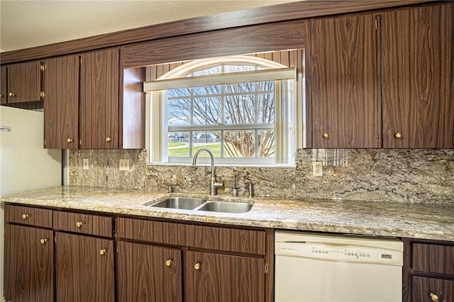 kitchen featuring white appliances, dark brown cabinetry, sink, and backsplash