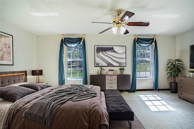 carpeted bedroom featuring multiple windows and ceiling fan