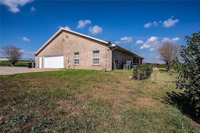 view of side of property featuring central AC, a garage, and a yard