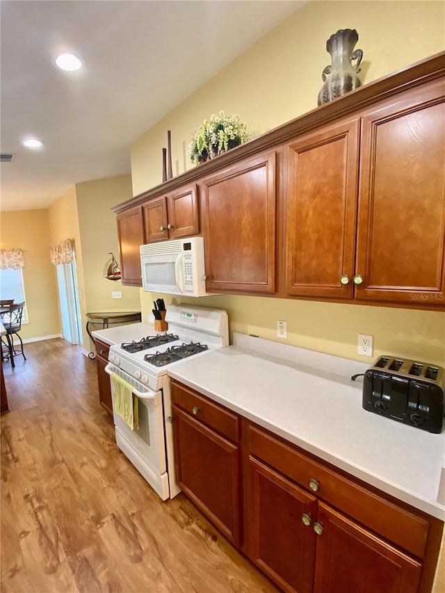 kitchen with white appliances and light hardwood / wood-style floors