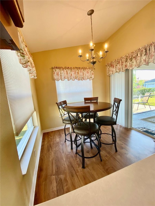 dining area featuring lofted ceiling, dark wood-type flooring, and an inviting chandelier