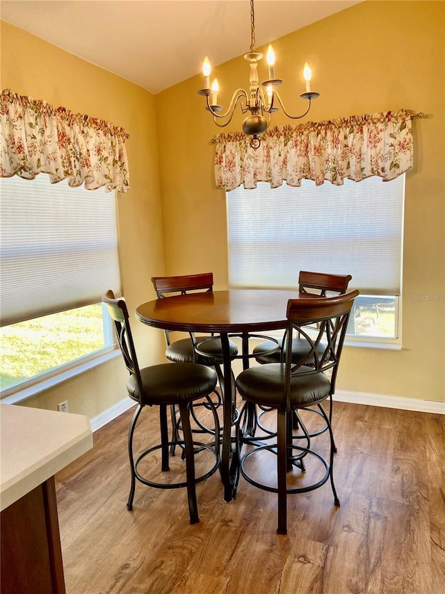 dining area with an inviting chandelier, hardwood / wood-style flooring, and vaulted ceiling