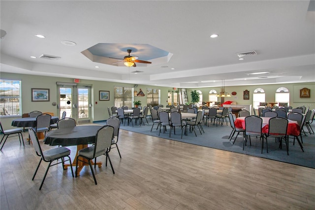 dining room featuring hardwood / wood-style flooring, a raised ceiling, ceiling fan, and french doors