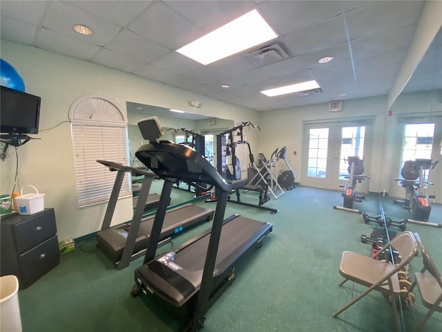 gym with a paneled ceiling and french doors