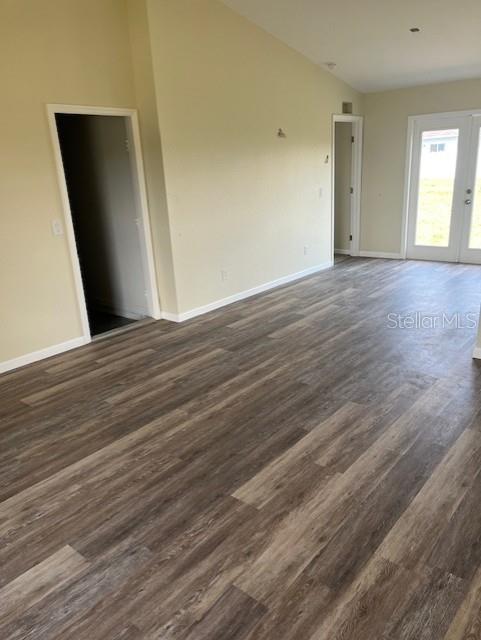 unfurnished room with dark hardwood / wood-style flooring, high vaulted ceiling, and french doors