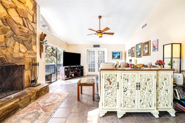 living room featuring french doors, a stone fireplace, high vaulted ceiling, ceiling fan, and tile patterned flooring