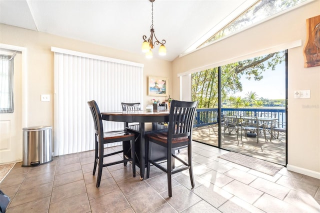 tiled dining area featuring a notable chandelier, a water view, and lofted ceiling