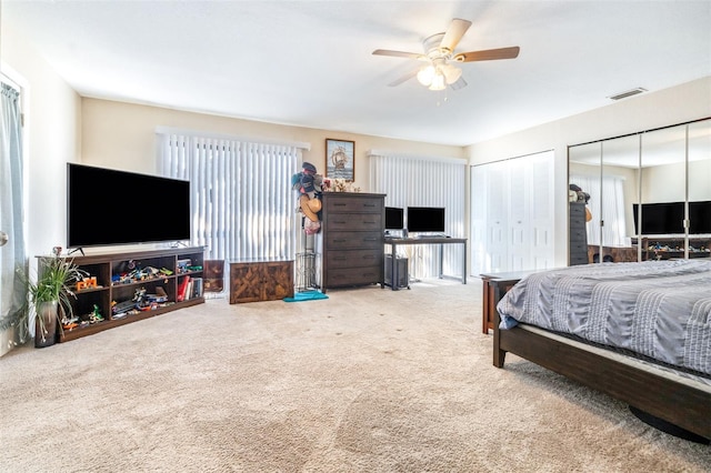 bedroom with two closets, carpet floors, and ceiling fan