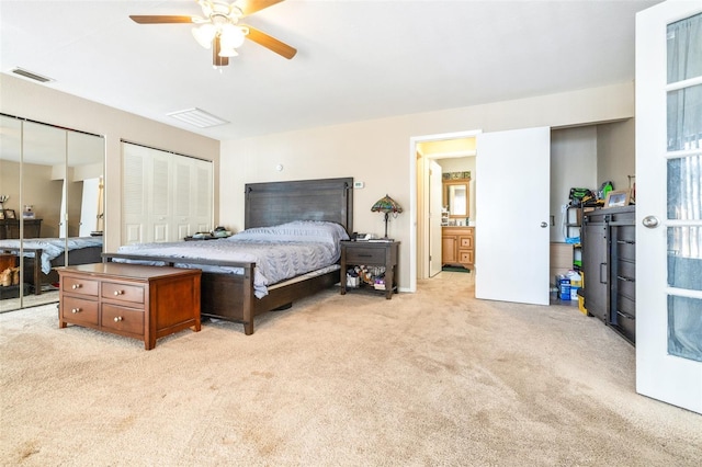 bedroom with multiple closets, light colored carpet, ceiling fan, and ensuite bath