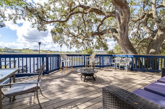 deck with a water view and a fire pit