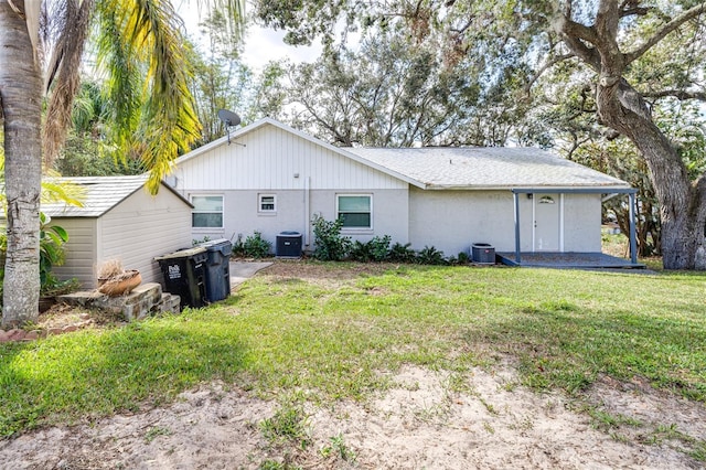 rear view of property featuring a lawn and central air condition unit