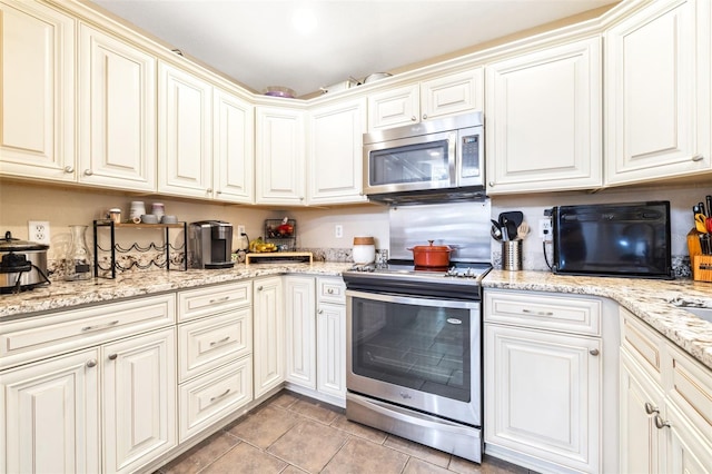 kitchen featuring light stone counters, stainless steel appliances, and light tile patterned floors