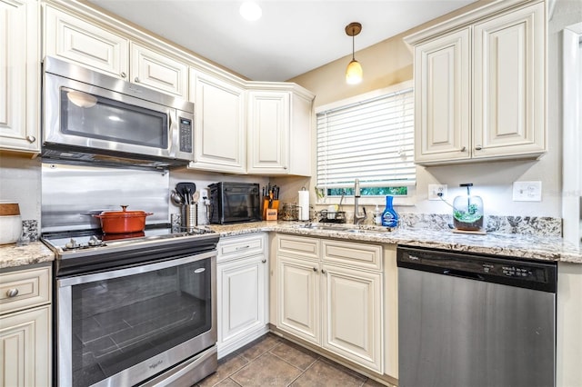 kitchen with stainless steel appliances, decorative light fixtures, light stone countertops, and sink