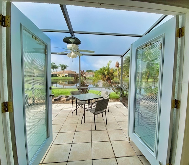 sunroom / solarium featuring ceiling fan and a water view