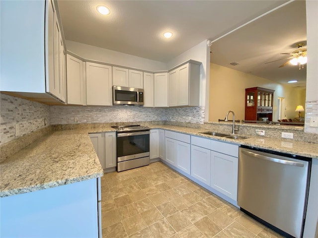 kitchen featuring light stone counters, appliances with stainless steel finishes, kitchen peninsula, and sink