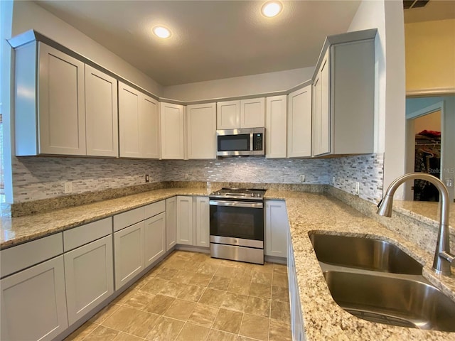 kitchen featuring sink, decorative backsplash, stainless steel appliances, and light stone countertops