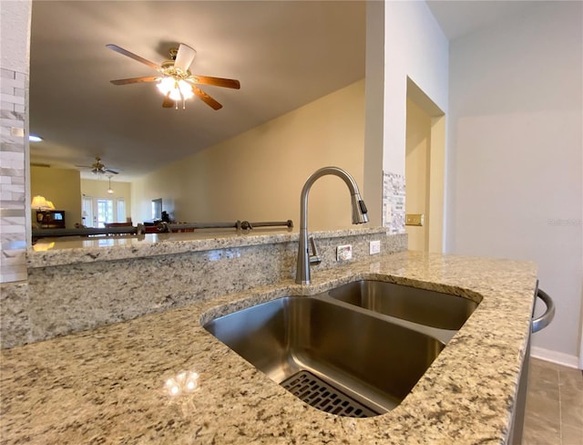 kitchen with light stone counters, ceiling fan, lofted ceiling, and sink