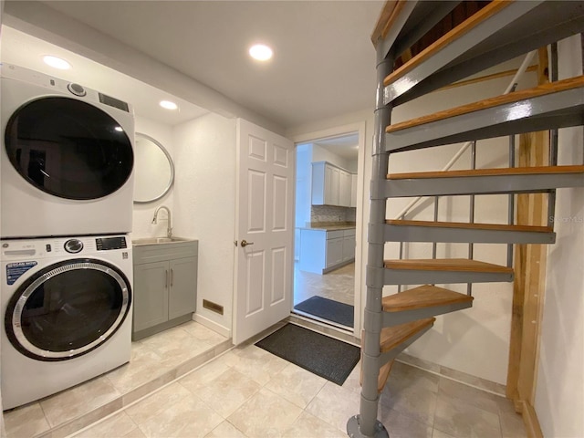 washroom featuring cabinets, stacked washer and clothes dryer, and sink