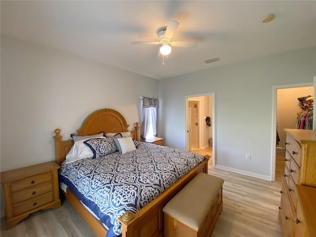 bedroom with a spacious closet, light hardwood / wood-style floors, ceiling fan, and ensuite bathroom