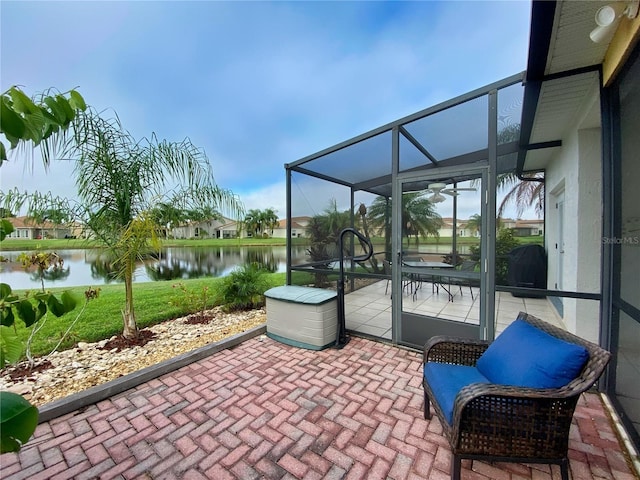 view of patio / terrace featuring a water view and glass enclosure