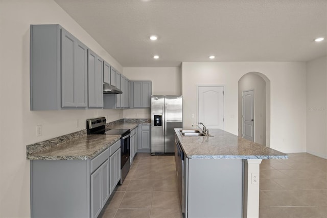 kitchen featuring sink, a center island with sink, light tile patterned floors, appliances with stainless steel finishes, and gray cabinets