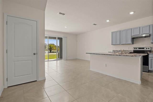 kitchen featuring light tile patterned floors, electric range, gray cabinets, light stone countertops, and a kitchen island with sink